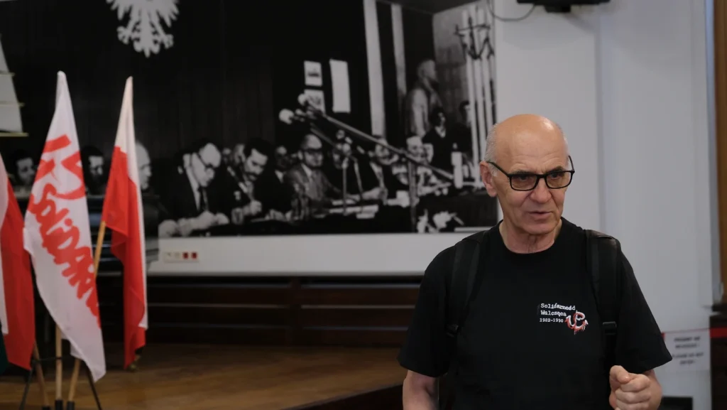 mężczyzna w czarnym tshircie na tle historycznego zdjęcia